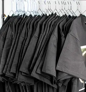 A rail of black t-shirts hanging in a small clothing studio