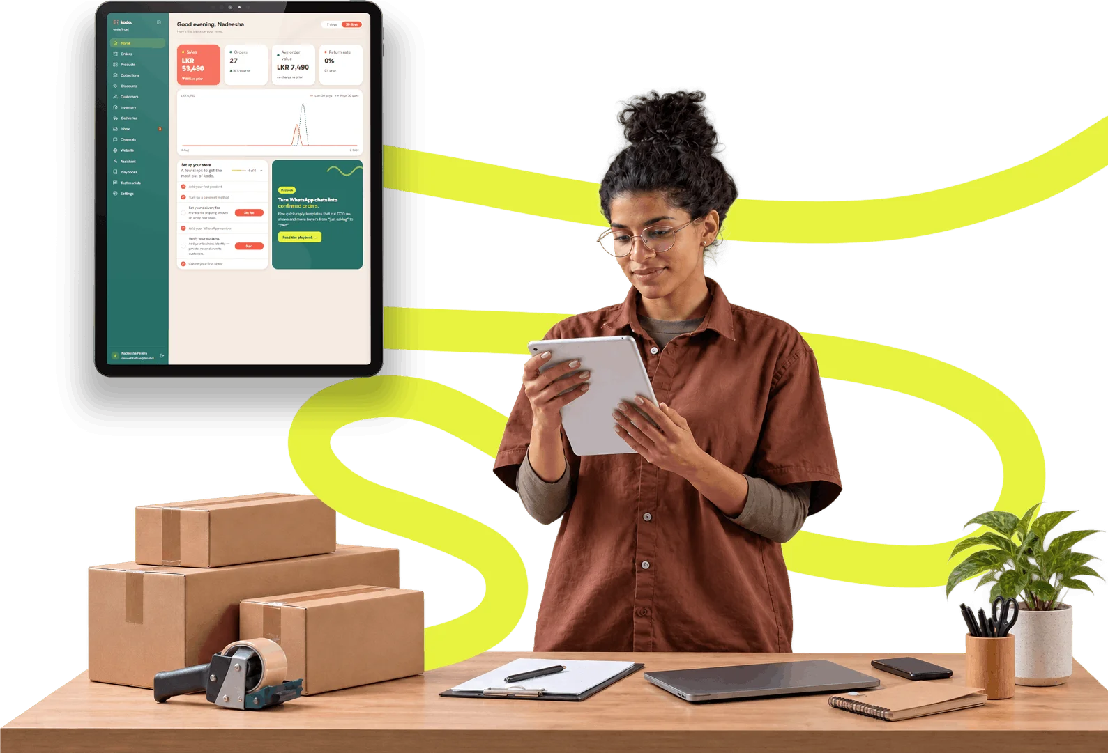 A Sri Lankan seller checking orders beside the kodo dashboard, surrounded by packed parcels